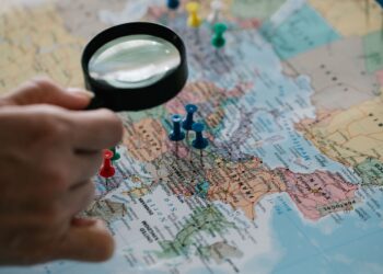 World map with route pins and travel planning flat lay